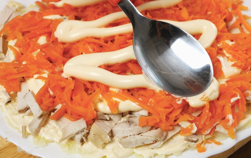 Половину курицы выложить на блюдо,  смазать майонезом, посолить, приправить, придав круглую форму. Затем – морковь (смазать майонезом).  