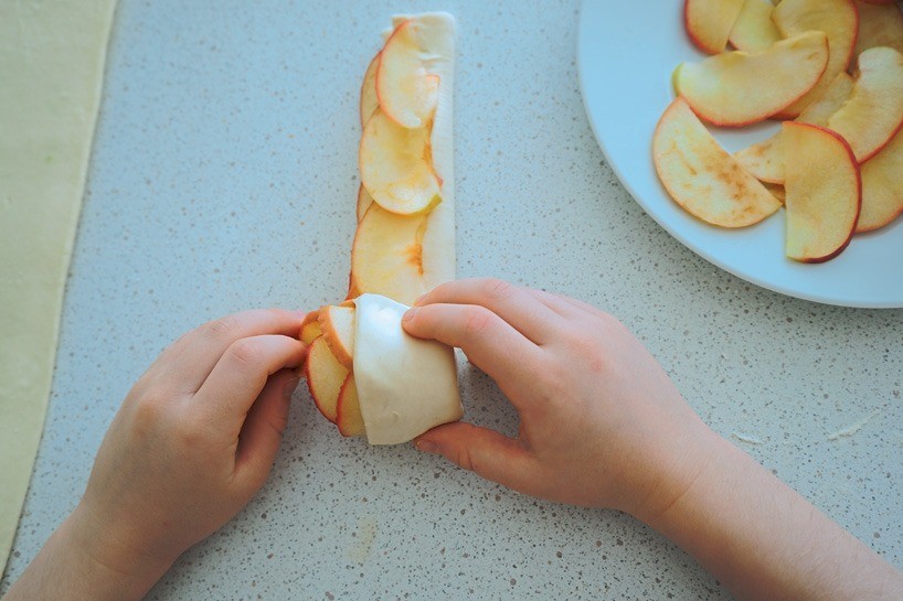 Накрой яблоки тестом и выложите второй слой яблочных ломтиков. Скрути рулончик. Лучше положить яблочные розы в небольшие формы для выпекания.