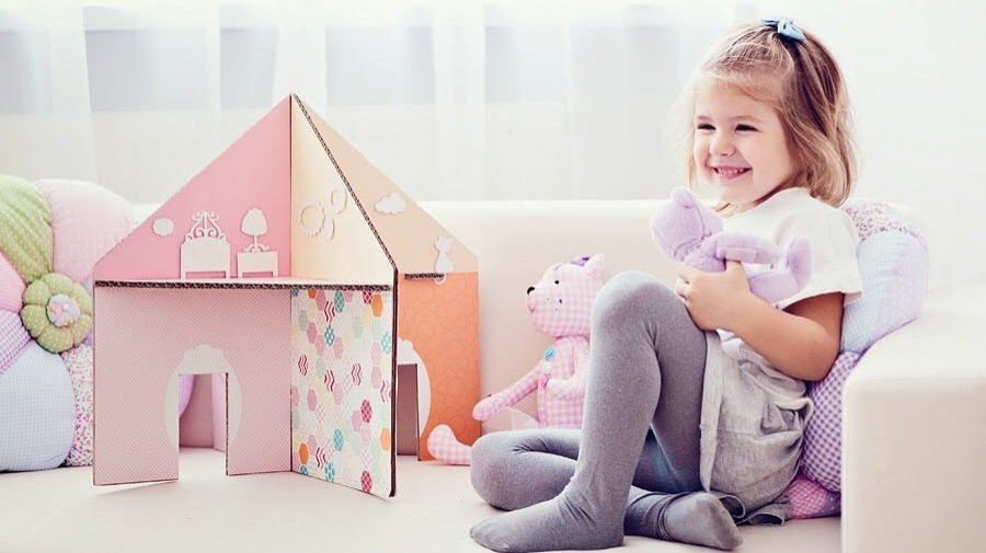 Возьми два больших листа картона и соедини их крест-накрест с помощью клея или скотча. Получится домик без пола и крыши.  Вырежь дверные проемы и обклей их цветной бумагой. 