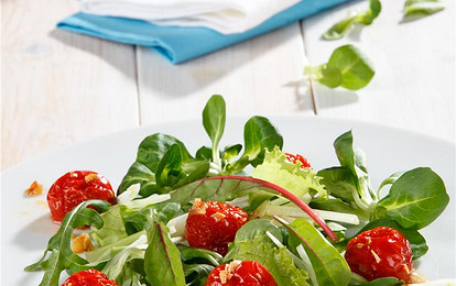 Листья разных видов салата с жареными помидорами и чесноком